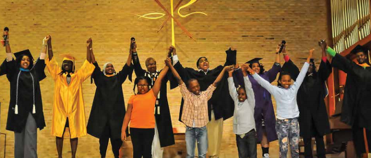 graduates and kids holding hands